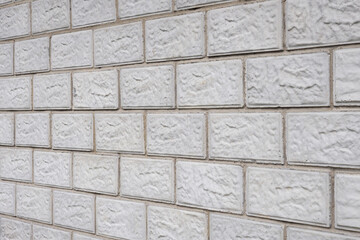 The wall of the house is made of gray concrete blocks. Background or wallpaper. The seams of the masonry go into the distance and form a perspective. Backdrop on the topic of housing renovation