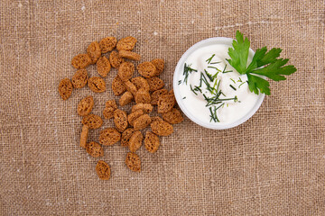 a stack of croutons breadcrumbs and a bowl of green onions and sour cream are spread out on the burlap. Top view.