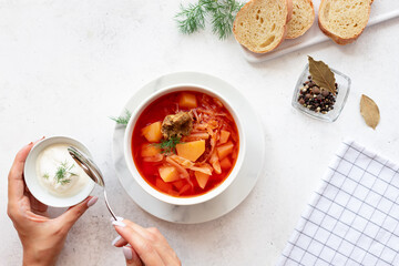 woman eating red borscht with vegetables, meat and sour cream. Traditional slavic dish with beetroot, cabbage, tomato. top view. White background. copy space