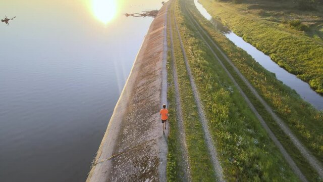 Runner stop because a muscular injury during his training on a small road close to the lake. Aerial footage
