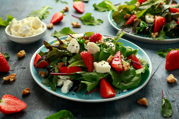 Goats cheese and strawberry summer salad served with nigella and sesame seeds drizzled with runny honey