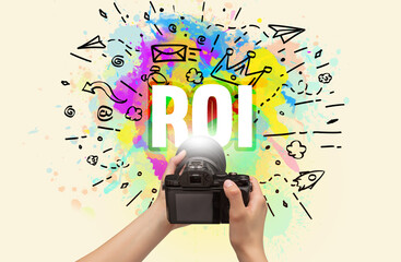 Close-up of a hand holding digital camera with abstract drawing and ROI inscription