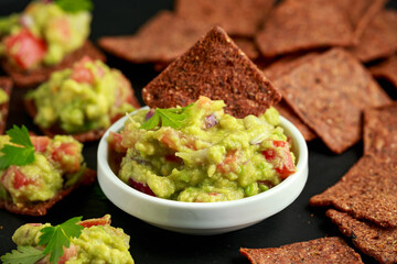 Avocado Guacamole with chipotle and poblano whole grain tortilla chips on rustic stone board