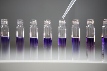 Analytical chemistry background. Small vials of purple chemical in a pharmaceutical laboratory. Vaccine testing