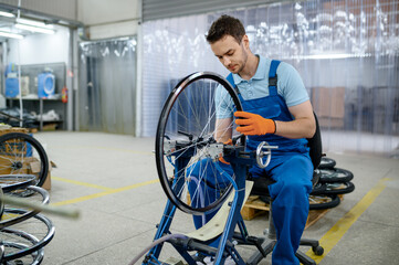 Male worker at the machine tool checks bicycle rim