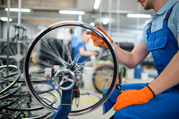 Male worker at the machine tool checks bicycle rim