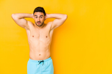 Fototapeta premium Young caucasian man with swimsuit isolated on yellow background Young caucasian man with trscreaming, very excited, passionate, satisfied with something.