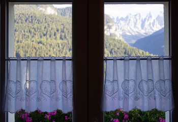 Detail of the window of the mountain house with embroidered white curtains.