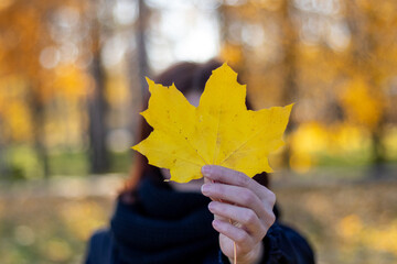 A girl holding a yellow sheet in front of her face