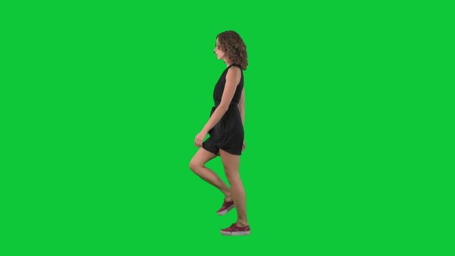 Confident beauty woman fashion model walking on catwalk runway. Full body side view on green screen chroma key background. 
