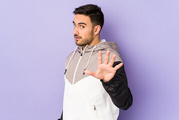 Young caucasian man isolated on purple background indicates with both fore fingers up showing a...