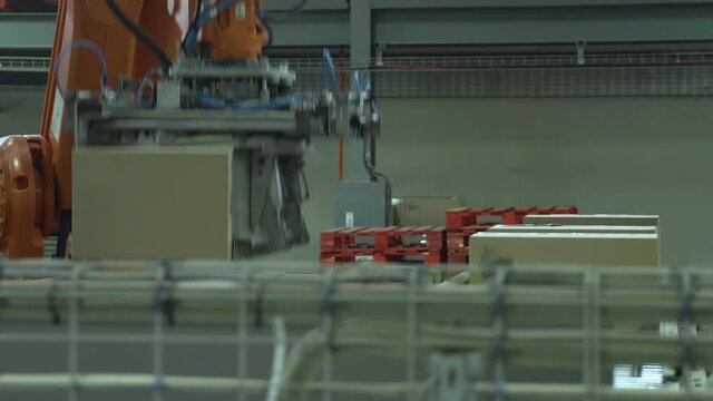 A busy automated warehouse shipping depot with robotic arm picking up packages from conveyor belt.
