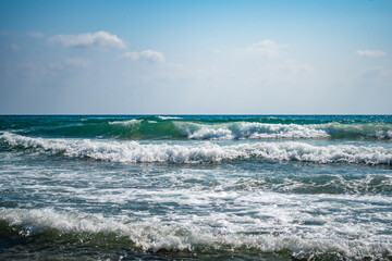 Beautiful sea waves splash with white foam on a blue ocean surface background.