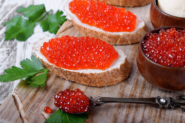 Sandwiches with bran bread, red caviar and butter on the wooden board