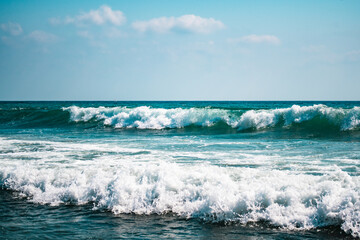 Beautiful sea waves splash with white foam on a blue ocean surface background.