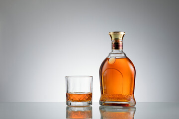 close up view of bottle of whiskey and a glass aside on grey back. 