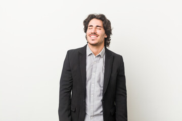 Young business man against a white background laughs and closes eyes, feels relaxed and happy.