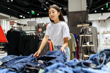 Cheerful woman choosing jeans in clothing store