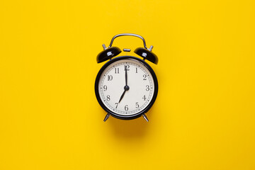 alarm clock shows 7 o'clock on a yellow background