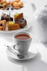 Close up view of dessert plate, china teapot and cups on white background