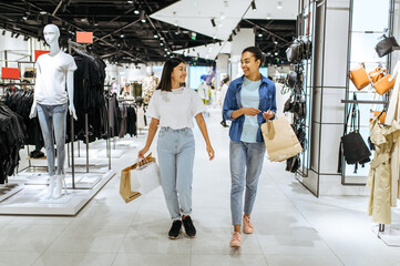 Girlfriends with bags walks in clothing store