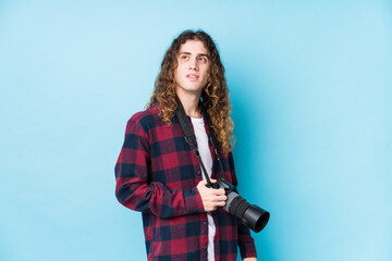 Young caucasian photographer man isolated looks aside smiling, cheerful and pleasant.