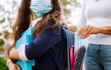 Young mother puts a protective sterile mask in a schoolgirl's backpack. Life during covid-19...