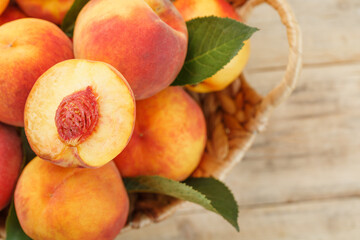 Peaches in a basket on a wooden background with a slice of sliced juicy peach with a stone.