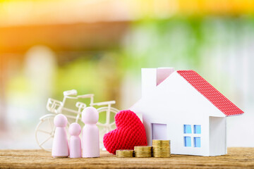 Family wood and red heart and house and stack gold coin put on the wood on sunlight in the public park, Loan for business investment real estate or saving money for buy home to one's love concept.
