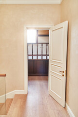 Opened white door to the home library with wooden balustrade. Classic style white door