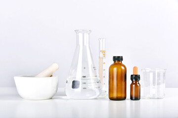 Group of scientific laboratory glassware with medicine bottles and clear liquid solution, Drug...