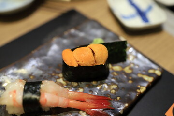 Sea urchin sushi wrapped in seaweed on a traditional Japanese dish in a Japanese restaurant. © Chanawat
