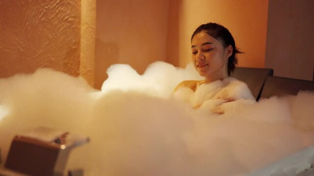 woman taking a bubble bath in the bathtub at the night

