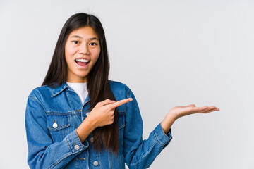 Young asian woman excited holding a copy space on palm.