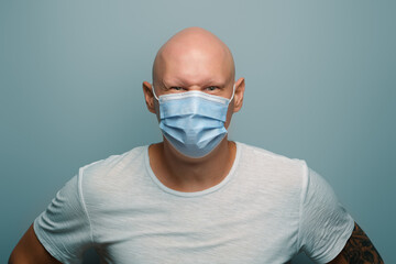 Bald angry emotional man wearing protective mask.