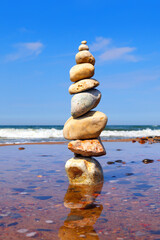 Fototapeta na wymiar Rock zen pyramid of colorful pebbles standing in the water on the background of the sea