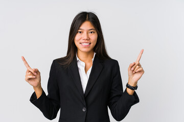 Young asian business woman indicates with both fore fingers up showing a blank space.