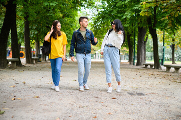 Happy students outdoor walking and talking to each other, full length