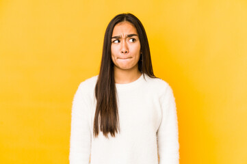 Fototapeta premium Young woman isolated on a yellow background confused, feels doubtful and unsure.