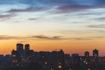Close up picture of silhouette of the city with orange sky in sunset time. Kyiv view with small houses on the horizon with amazing sky and clouds. Panorama of Kyiv city silhouette. Ukraine.