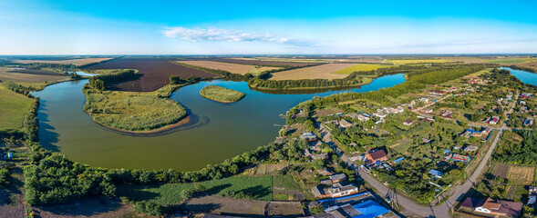 Fototapeta na wymiar Sunny summer and hot day - over the outskirts of the Kuban village of Sergievskaya near the Kirpili river with an island in summer Wheat fields are visible across the river.