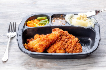 Butter knife adding to potatoes in a chicken TV dinner