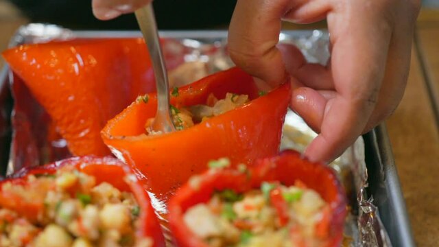 Isolated macro view of stuffing red sweet bell peppers with a savory vegan mixture - slow motion