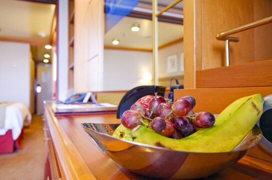 Wohnzimmer mit Obstkorb in Luxuskabine auf Kreuzfahrtschiff - Livingroom inside suite category stateroom or cabin with fresh fruit basket on luxury cruiseship or cruise ship liner