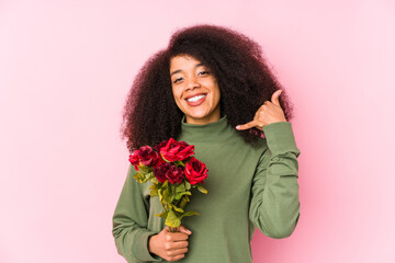 Young afro woman holding a roses isolated Young afro woman holding a rosesshowing a mobile phone call gesture with fingers.