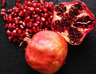 Macro photography of two organic pomegranates one whole and the other cut in half with its seeds on...