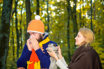 Fototapeta premium Sick man with napkin. Help with colds. Cold and flu remedies. Influenza, illness, sick, illness, coronavirus, epidemic. Bearded man in autumnal park. Man in warm sweater. Autumn.