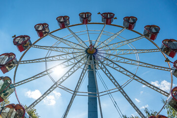 Fototapeta premium Ferris wheel with cabins in the shape of hearts on a background of blue sky. A romantic walk on the carousel.