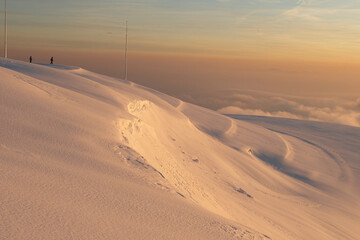 Fototapeta na wymiar Men hiking in the snow at sunset in Mount Grappa