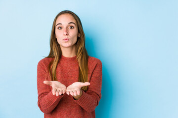 Obraz premium Young caucasian woman posing isolated folding lips and holding palms to send air kiss.